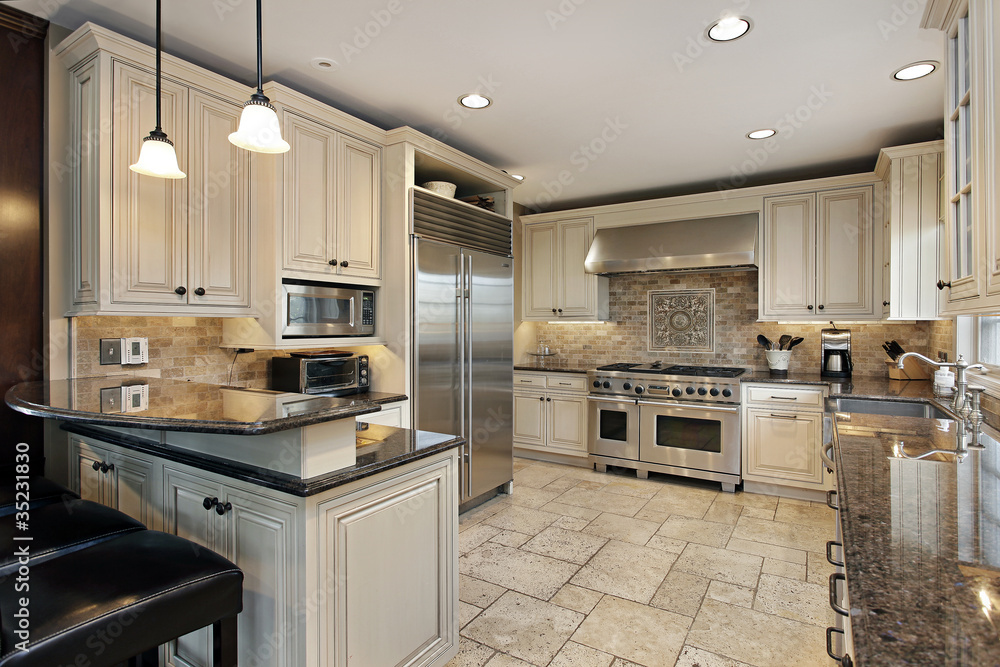 Modern kitchen with beige cabinets, stainless steel appliances, granite countertops, and tile flooring in a luxury home.