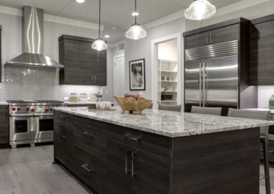 Modern kitchen with dark wood cabinets, granite island, stainless steel appliances, pendant lights, and sleek decor for Simone.