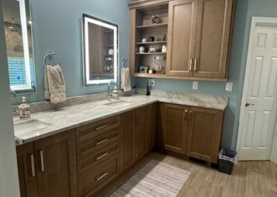 Modern bathroom with oak cabinets, LED mirror, granite countertop, light blue walls, and beige tiled flooring. - Milton GA by Simone Feldman Designs