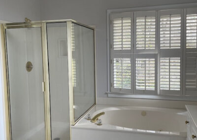 Luxury bathroom with gold-framed glass shower, jacuzzi tub, white shutters, and tiled floor, ideal for Simone home remodeling. Roswell GA