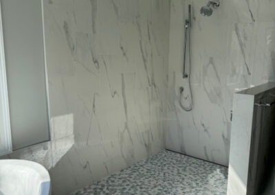 Luxury white marble shower with rainfall head, modern tiled floor, and spa-like soaking tub. - Roswell GA designed by Simone Feldman Designs.