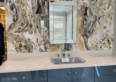 Modern bathroom with blue glossy cabinets, marble backsplash in gold and white swirl pattern, sleek mirror, and chrome sconces - Roswell, GA By Simone Feldman Designs